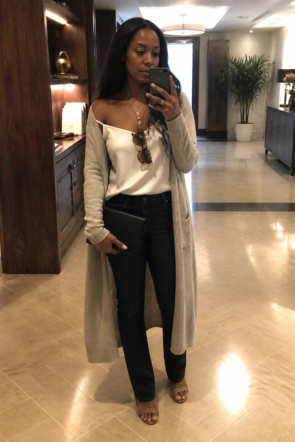 Woman in white off-shoulder top and long beige cardigan taking mirror selfie