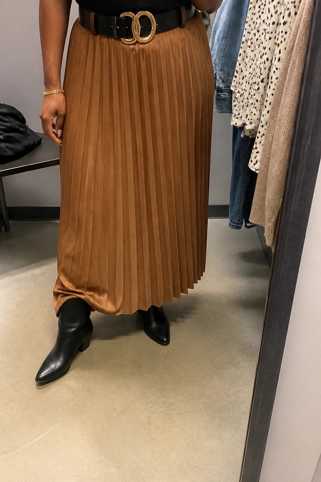 Brown pleated midi skirt with black belt and gold buckle, paired with black boots.