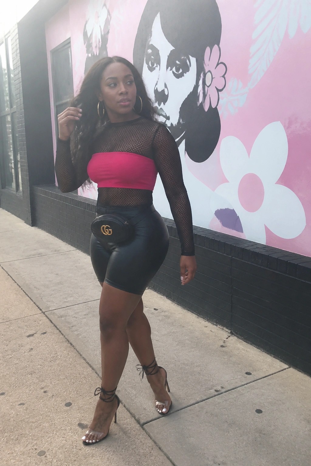Woman in pink bandeau and black mesh top with leather shorts by mural