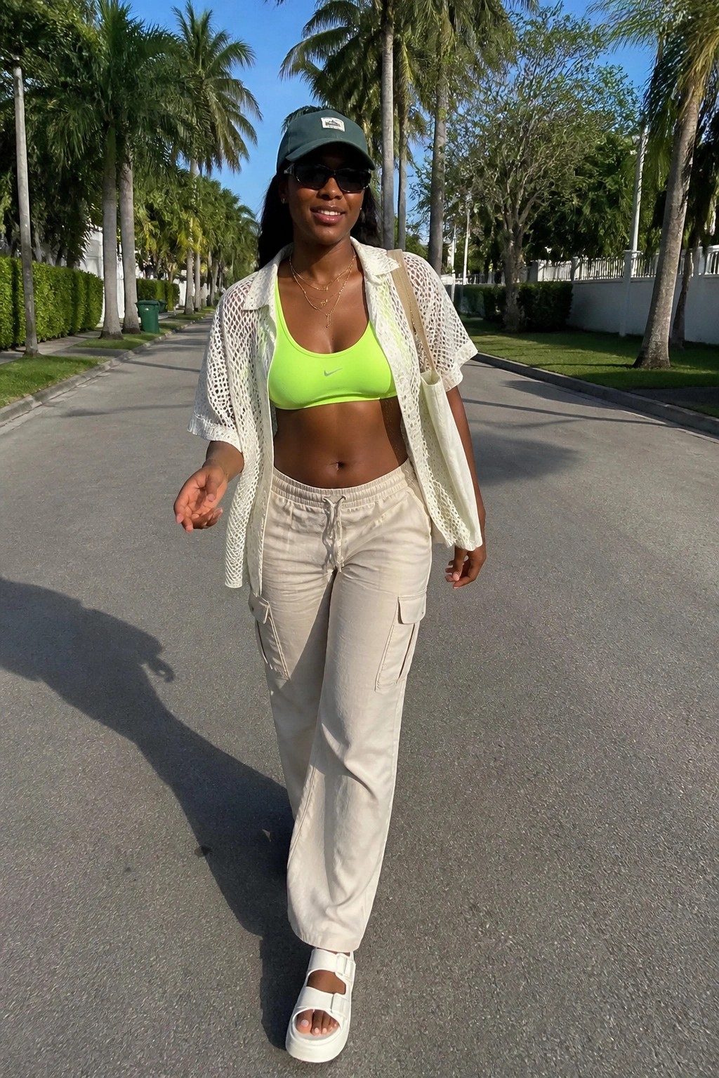 Woman in neon green sports bra, white mesh shirt, beige cargo pants on sunny path