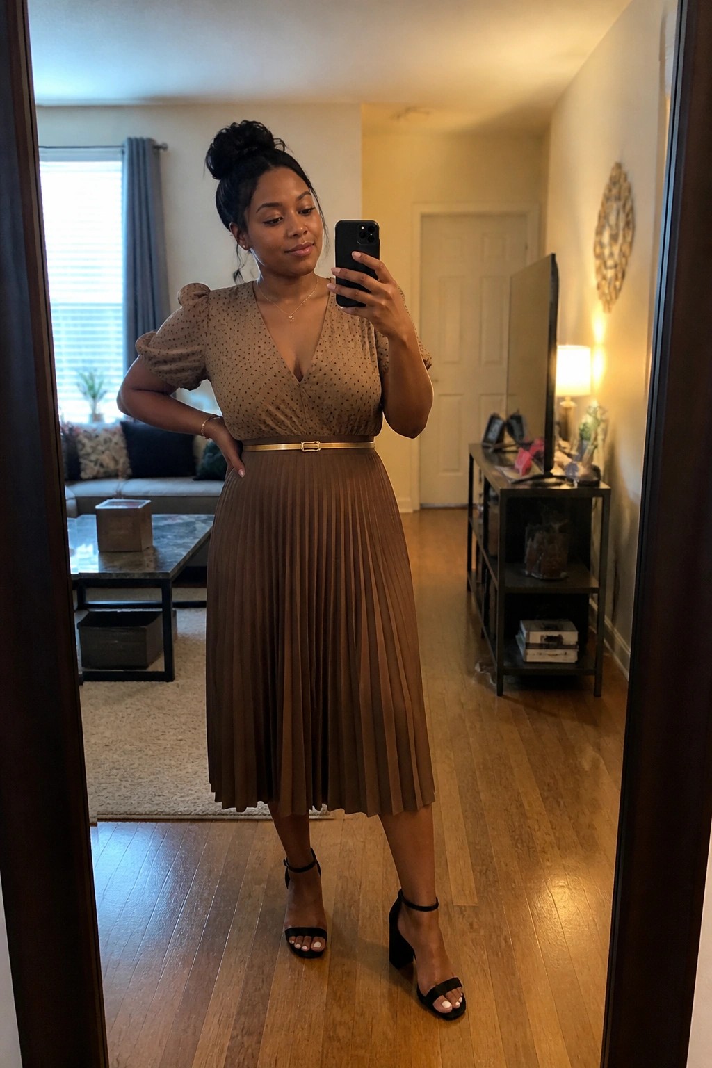 Woman in brown polka dot top and pleated skirt taking mirror selfie