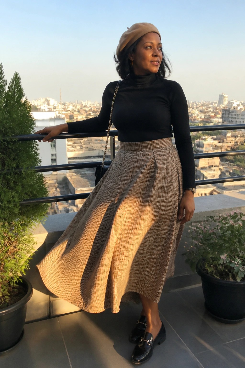 Woman in black turtleneck and checkered skirt with beret on city balcony