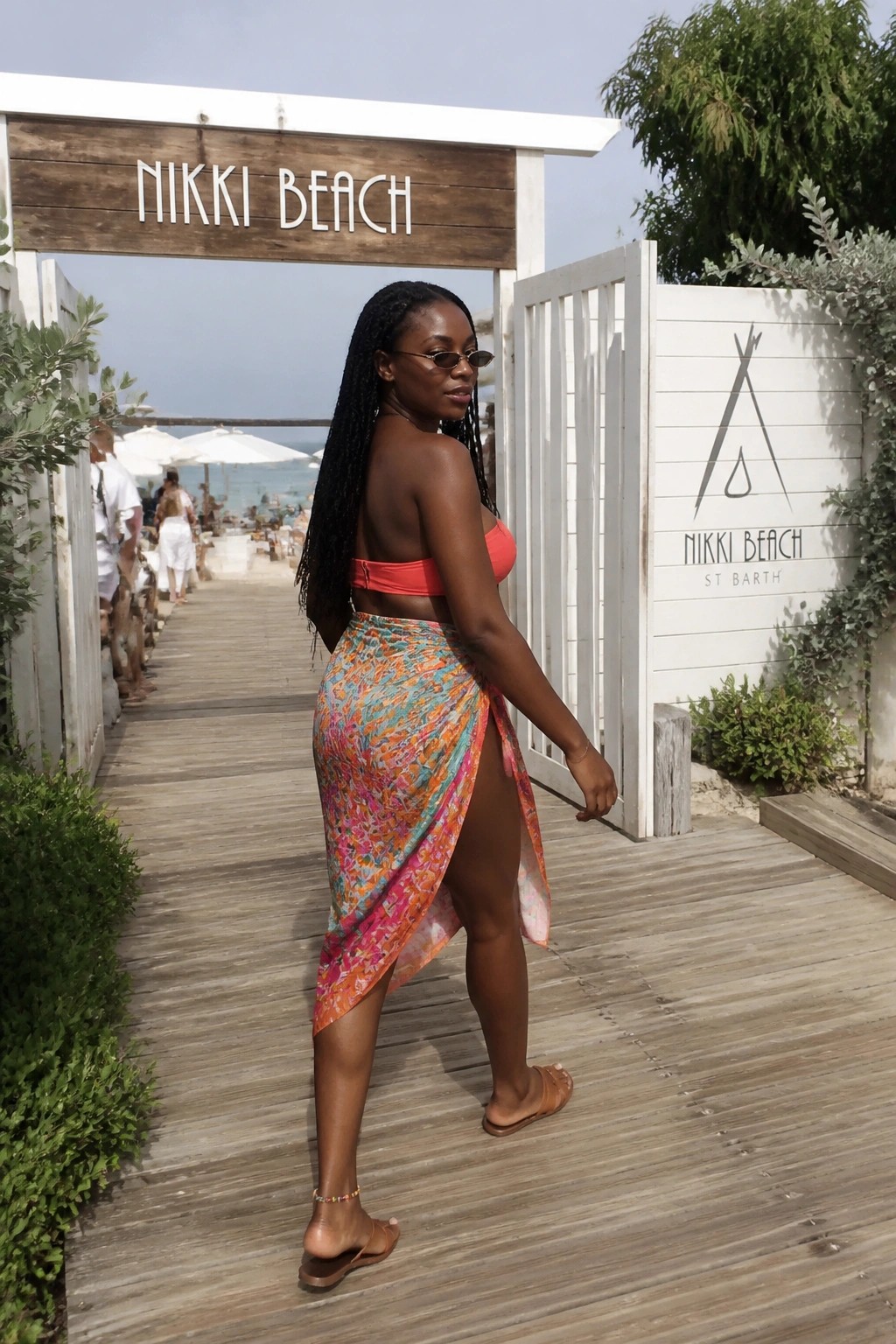 Woman with braids in orange top and colorful wrap skirt at Nikki Beach entrance