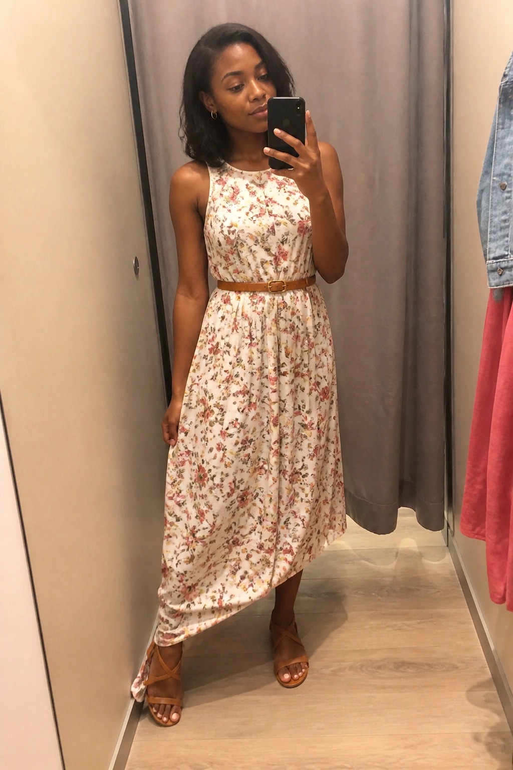 Woman in floral maxi dress taking mirror selfie in fitting room