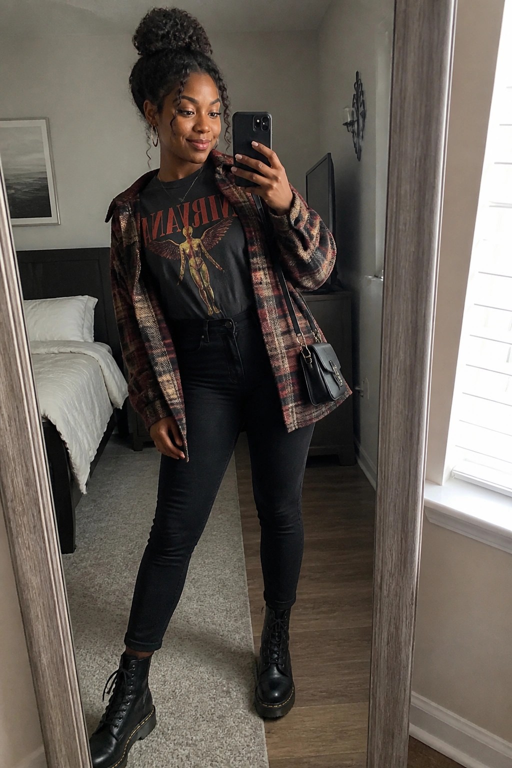 Woman in plaid flannel over Nirvana tee, black jeans, and combat boots taking mirror selfie