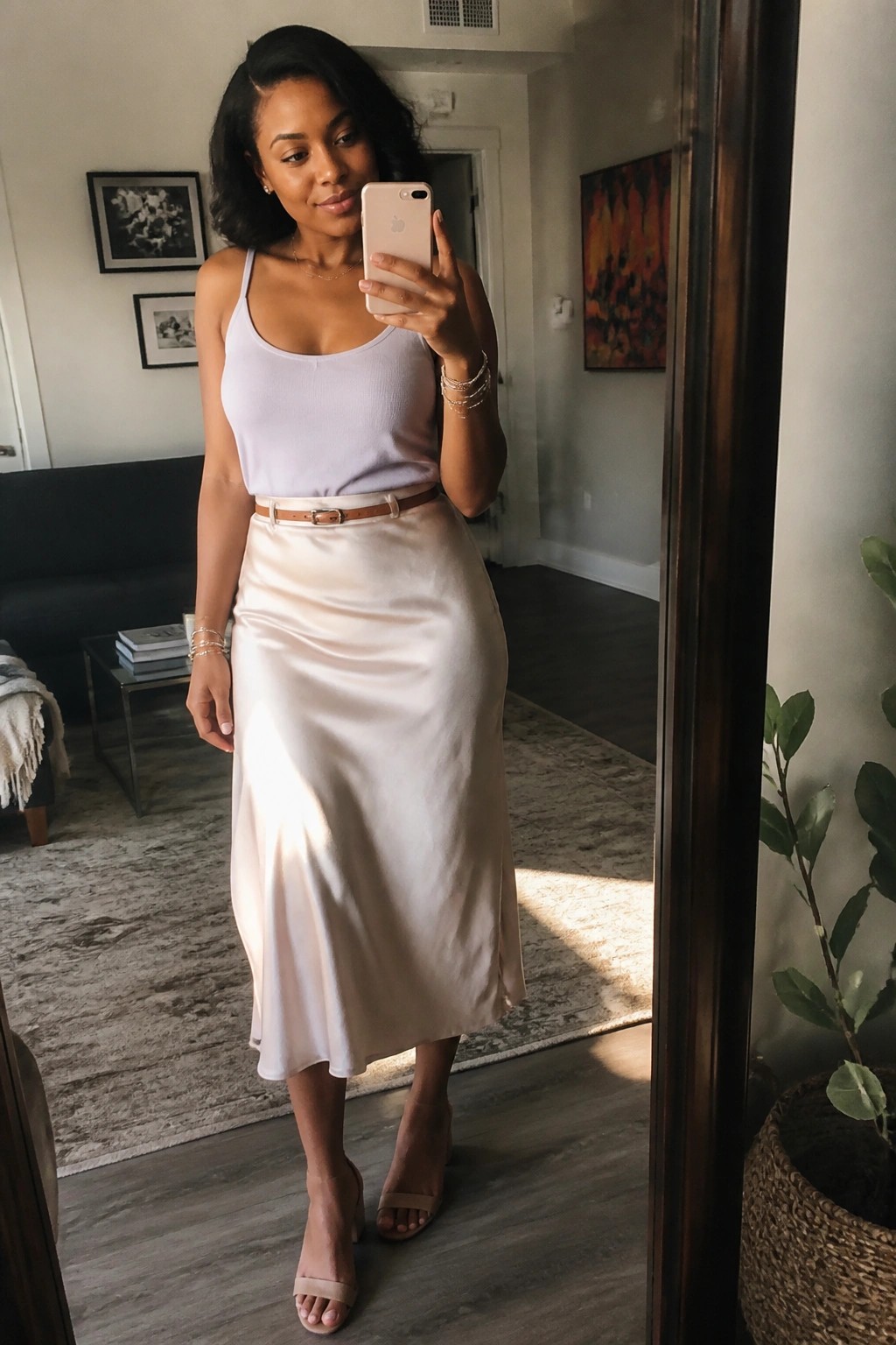 Woman in lavender top and satin skirt taking mirror selfie with phone