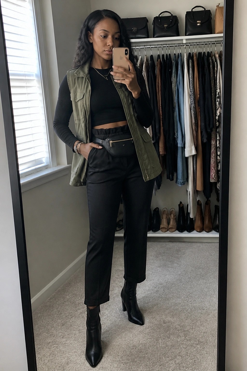 Woman in green utility vest taking mirror selfie in walk-in closet