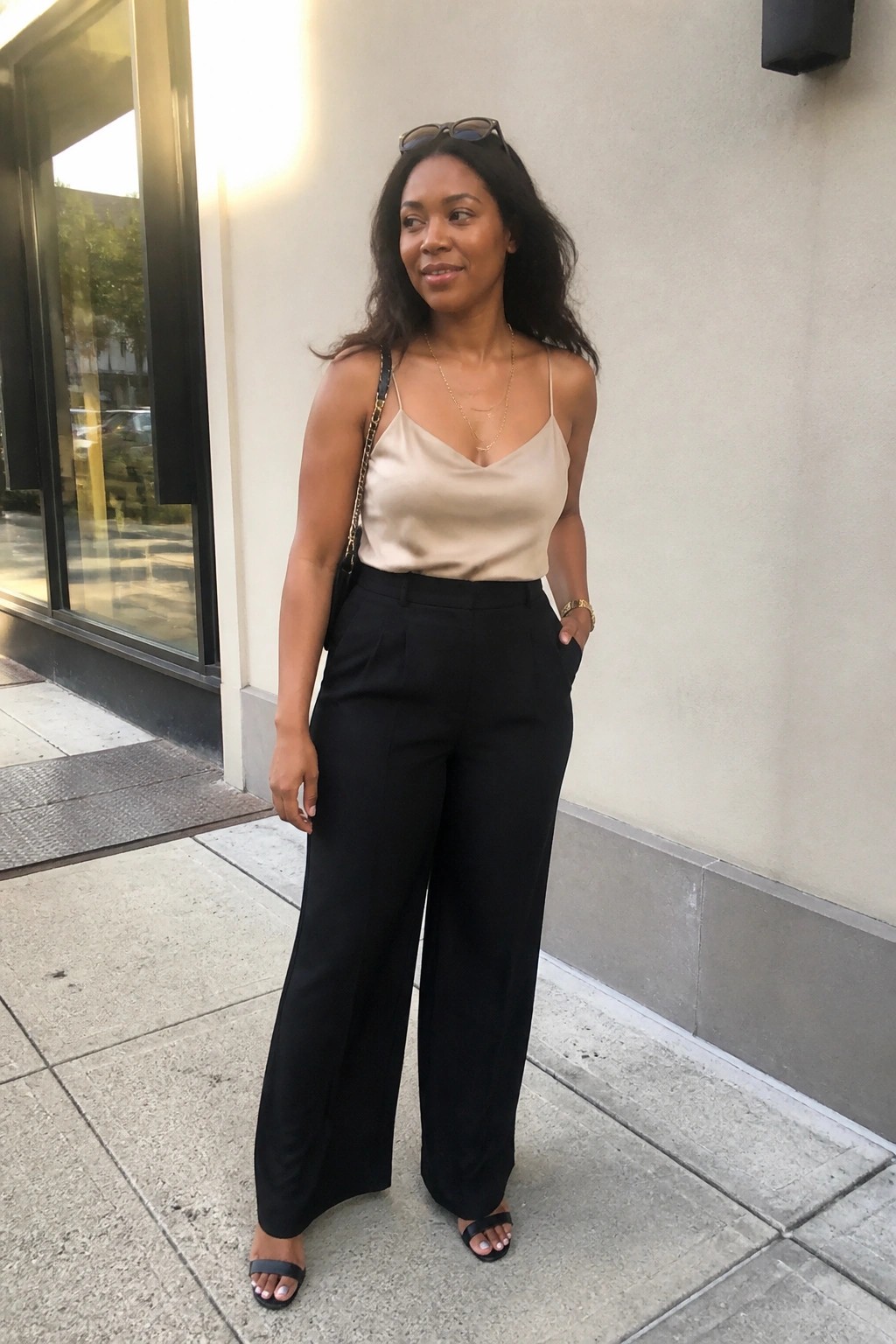 Woman in beige satin camisole and black wide-leg pants on sidewalk