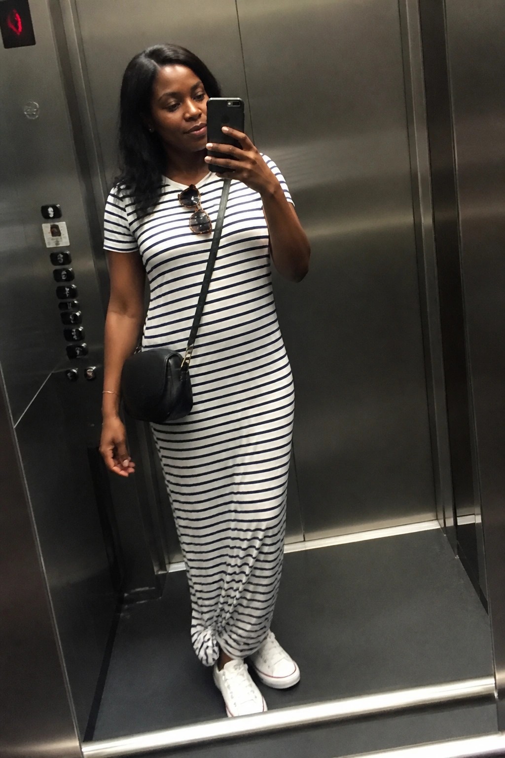 Woman in striped maxi dress taking selfie in elevator with white sneakers
