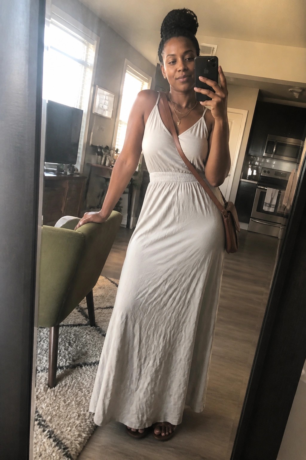Woman in white maxi dress taking mirror selfie in modern home interior