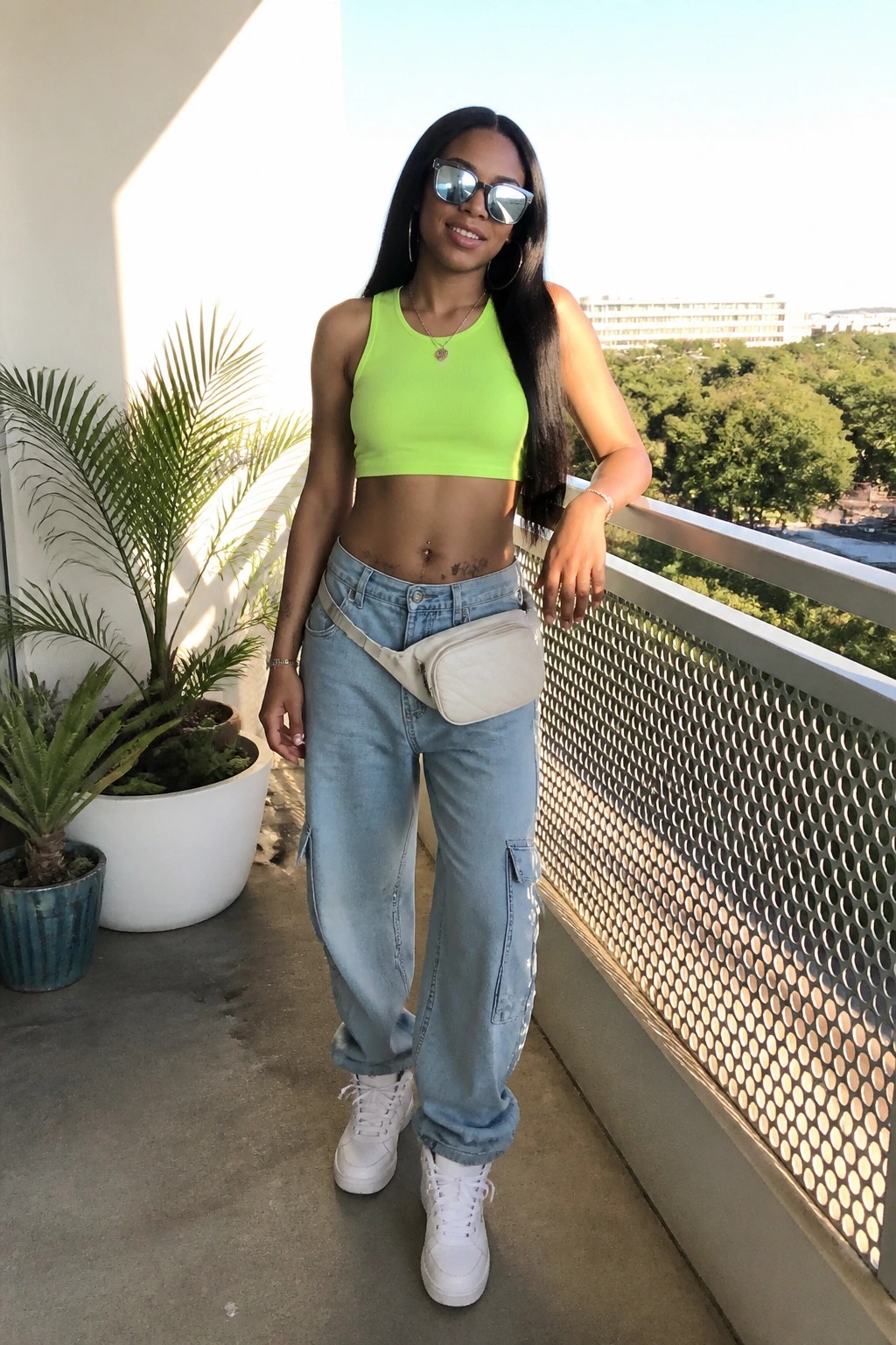 Woman in neon green crop top and light-wash cargo jeans on sunny balcony