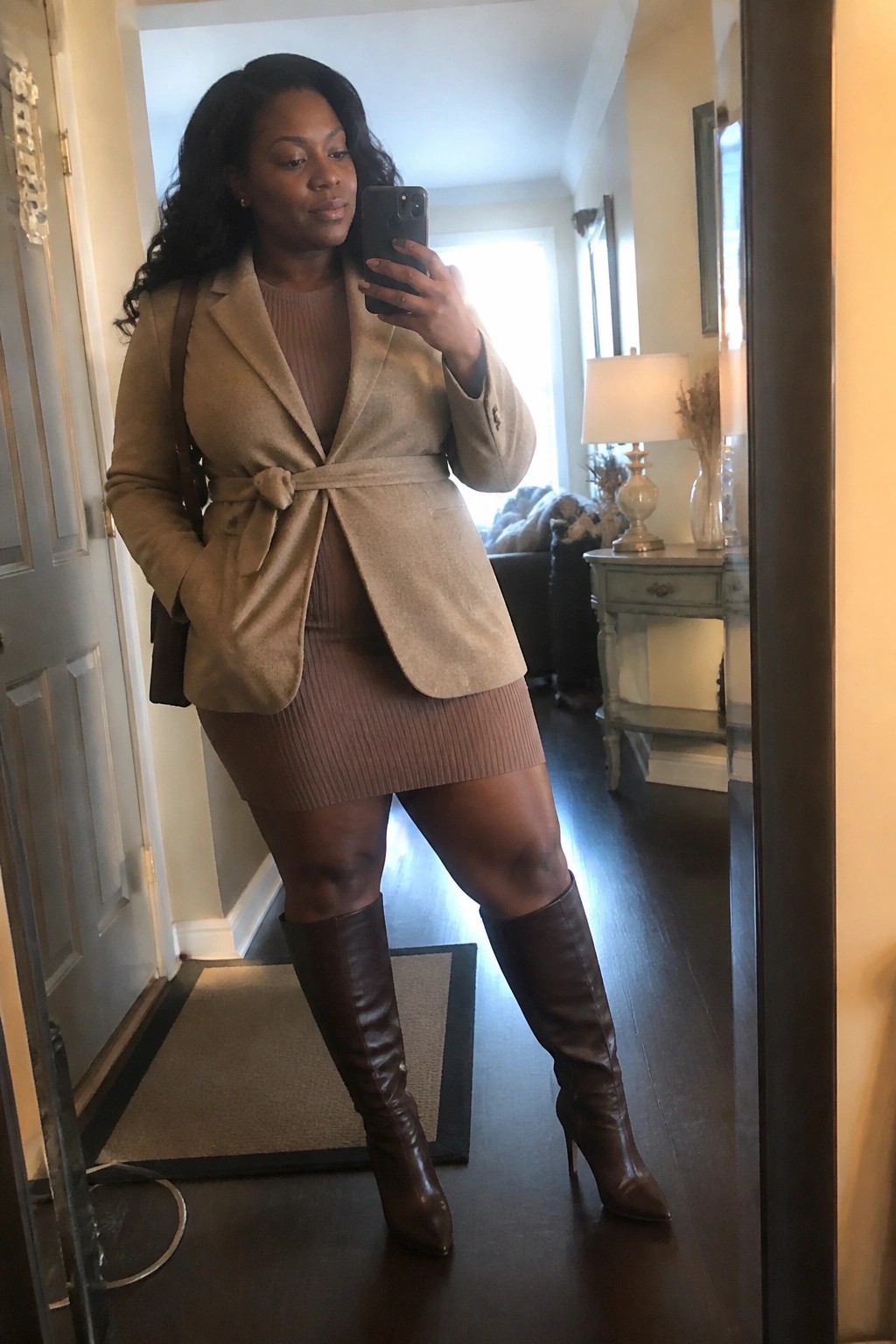 Woman in beige belted blazer and ribbed mini dress with brown knee-high boots