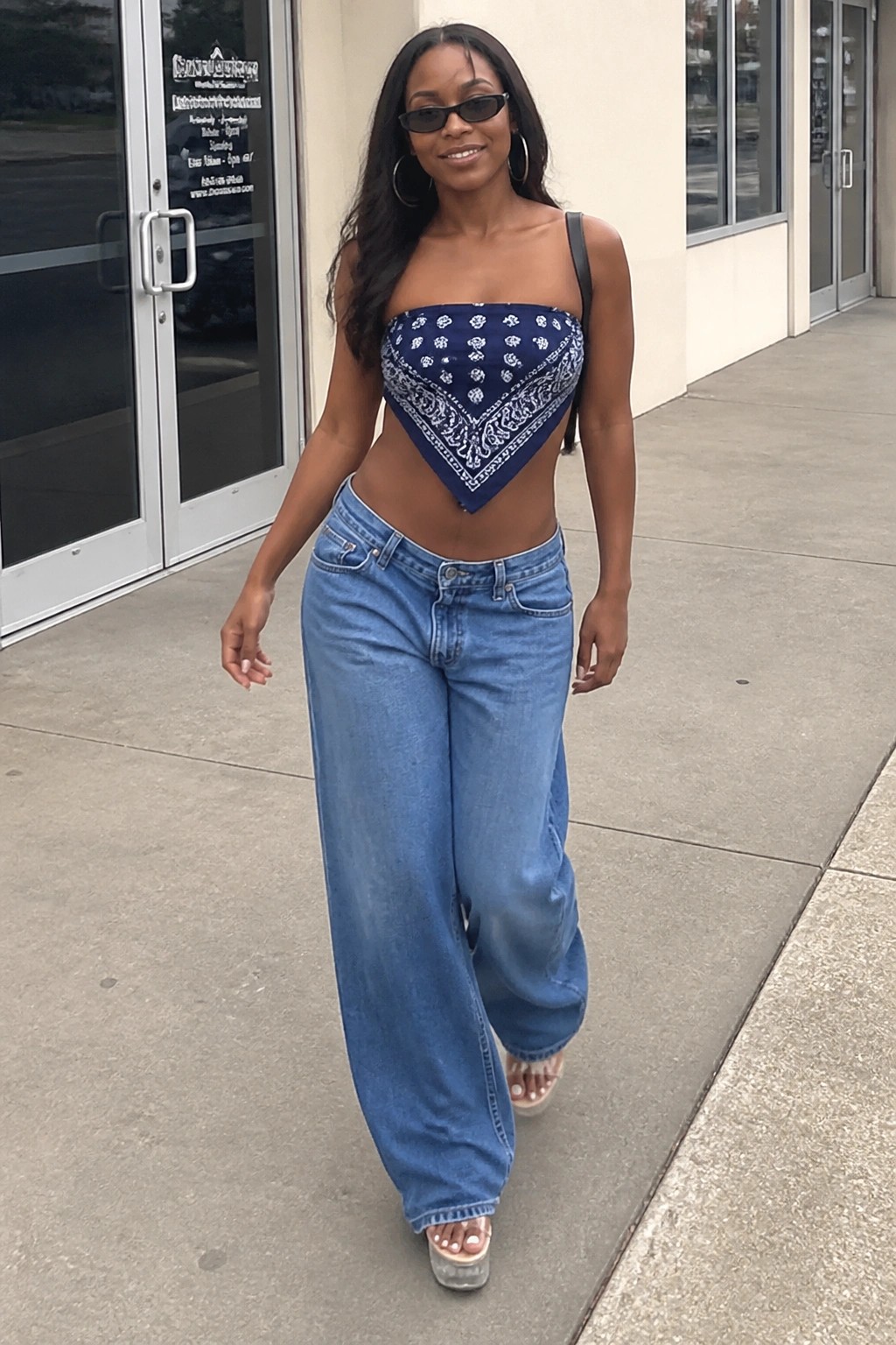 Woman in blue paisley bandana top and wide-leg jeans striding outdoors