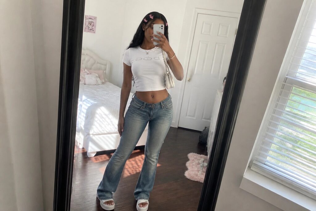 25 Y2K Outfits for Black Women With Nostalgic Trend Appeal Woman in light blue crop top and jeans taking bedroom mirror selfie with butterfly clips.