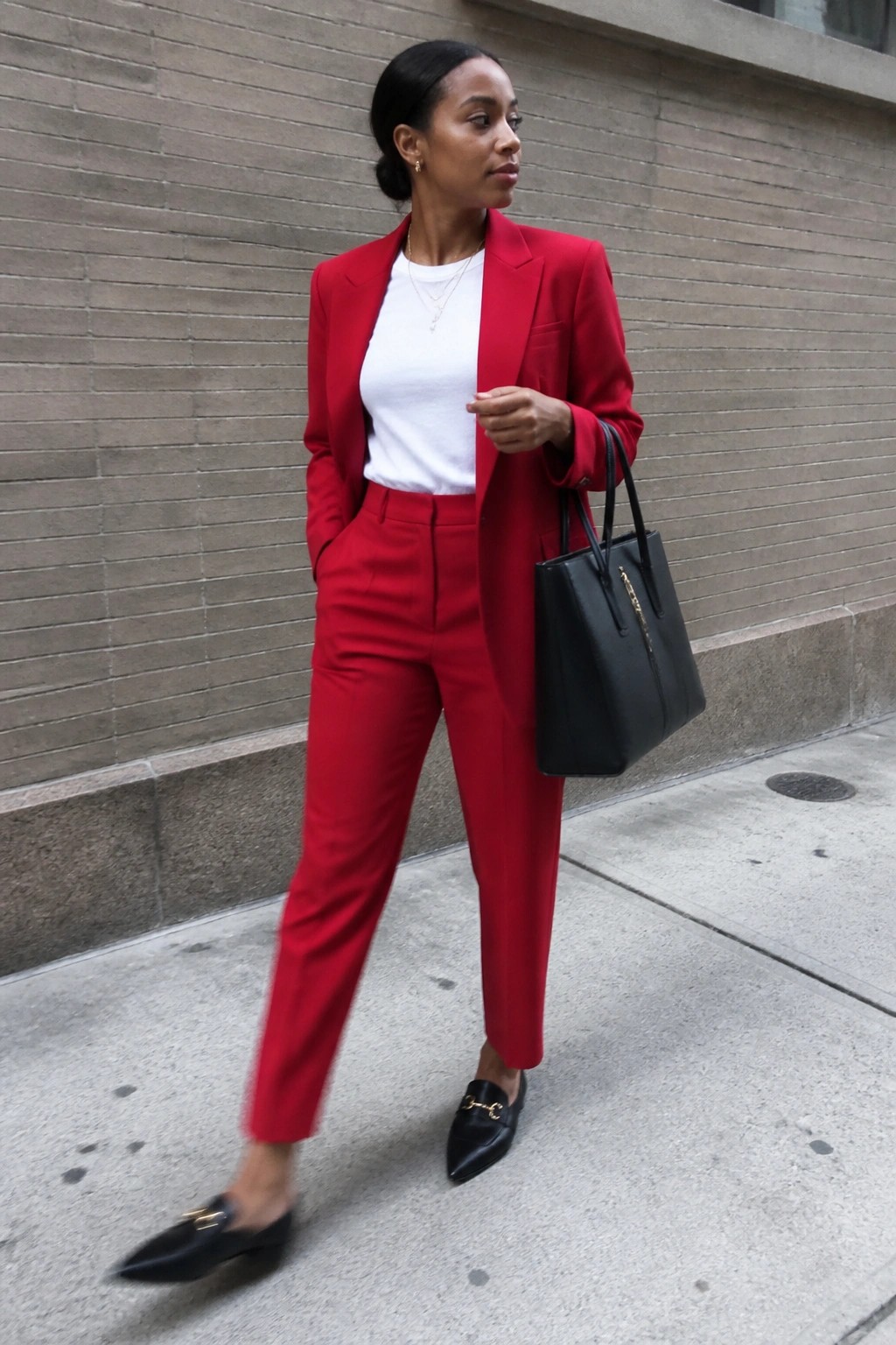 Woman in a red pantsuit over a white tee paired with black loafers and a black handbag.