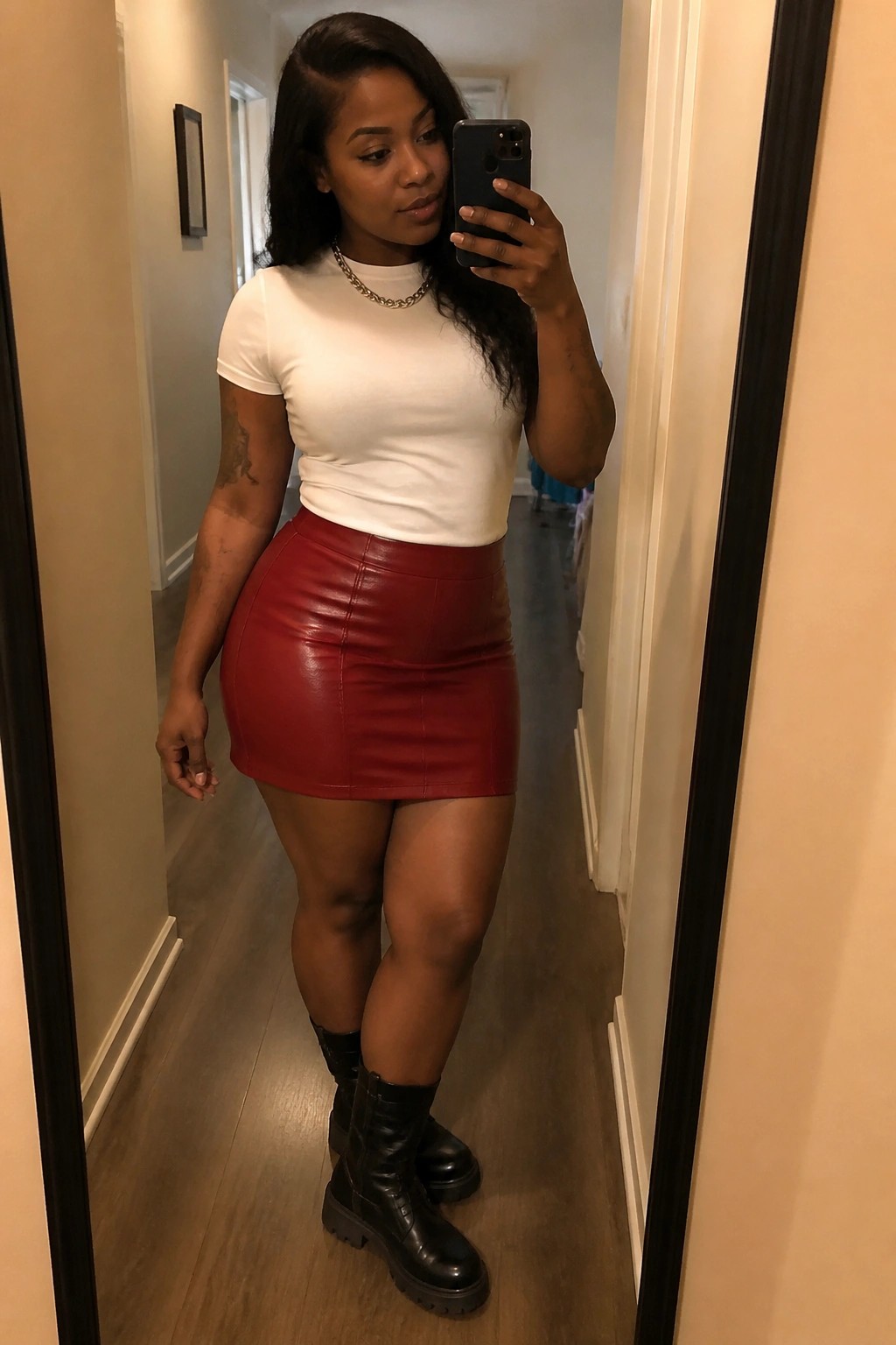Woman in white top and red leather mini skirt taking mirror selfie in hallway