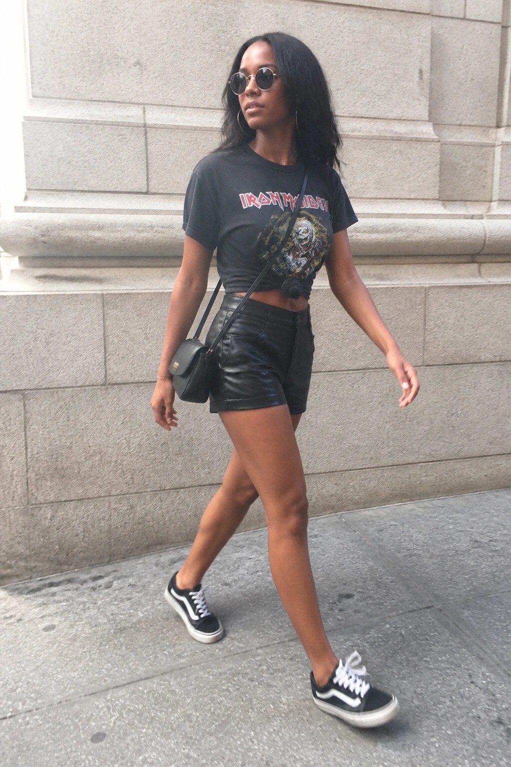Woman in cropped Iron Maiden tee and black leather shorts walking on sidewalk