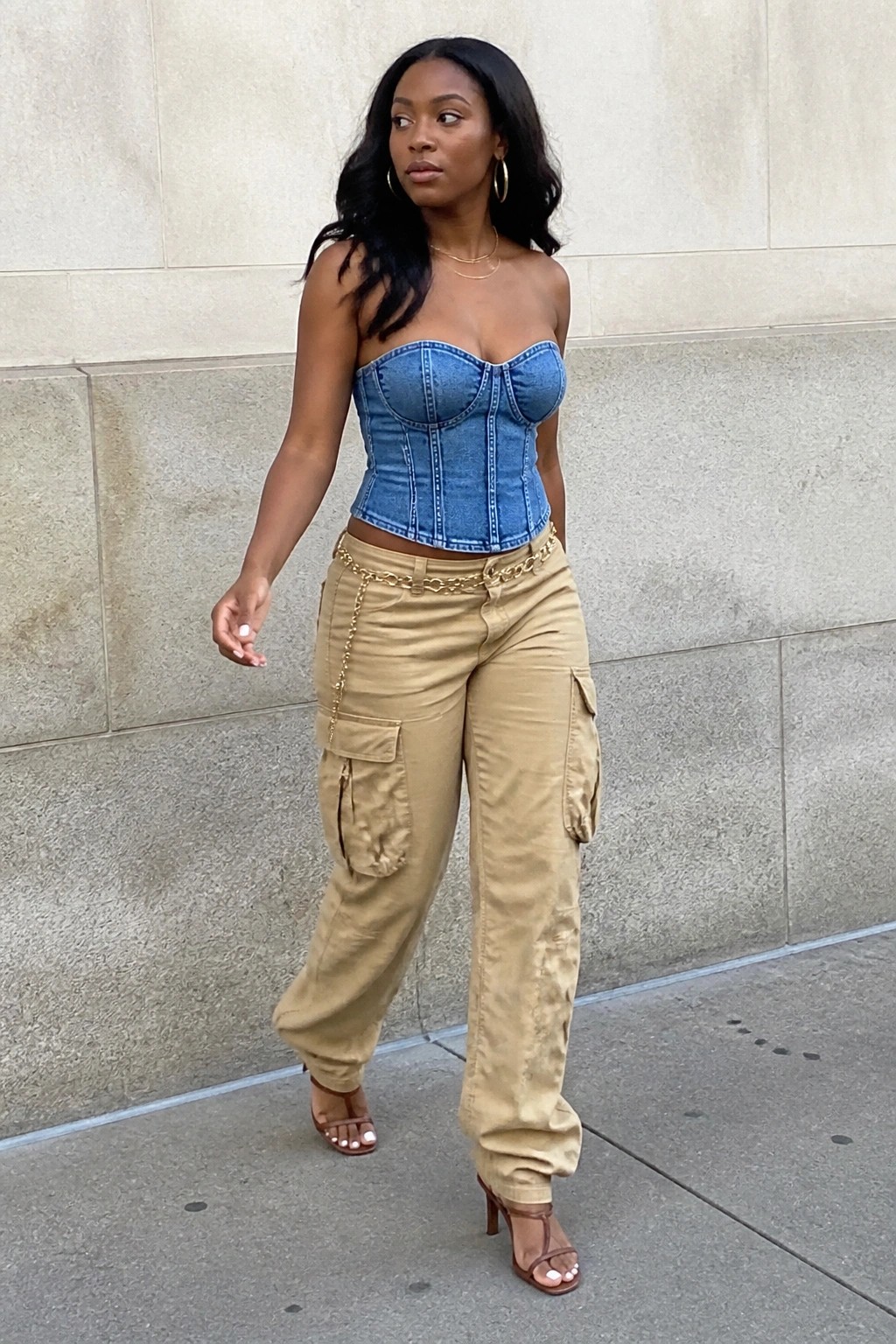 Woman in blue denim corset top and tan cargo pants with gold chain belt outdoors