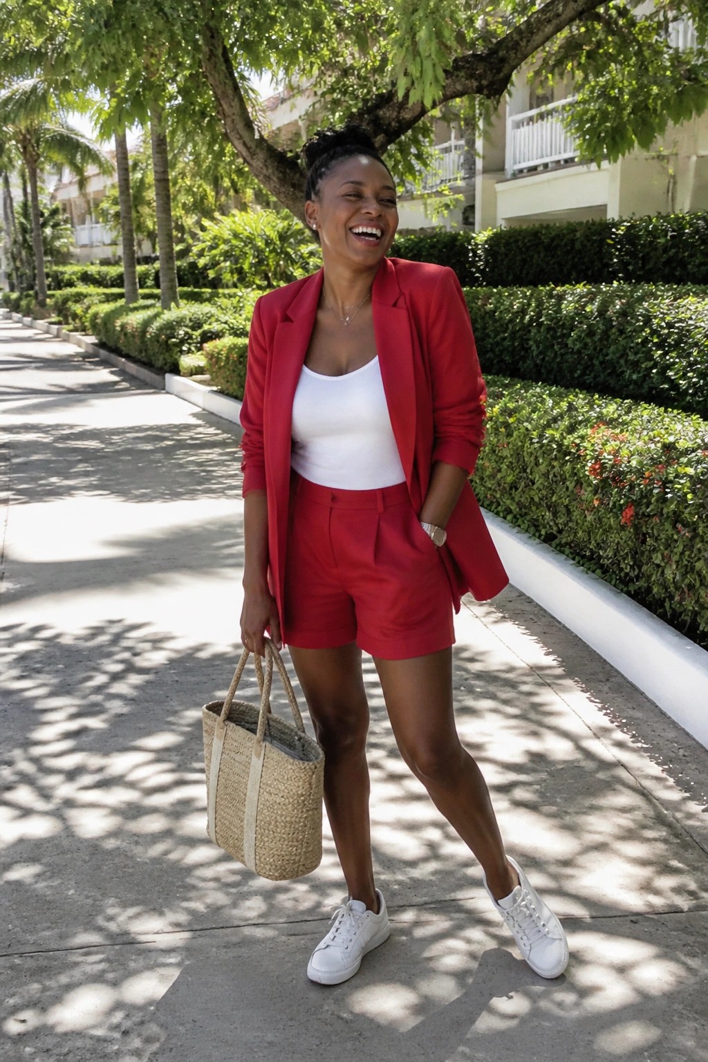 Woman in red blazer and shorts holding straw tote on sunny path