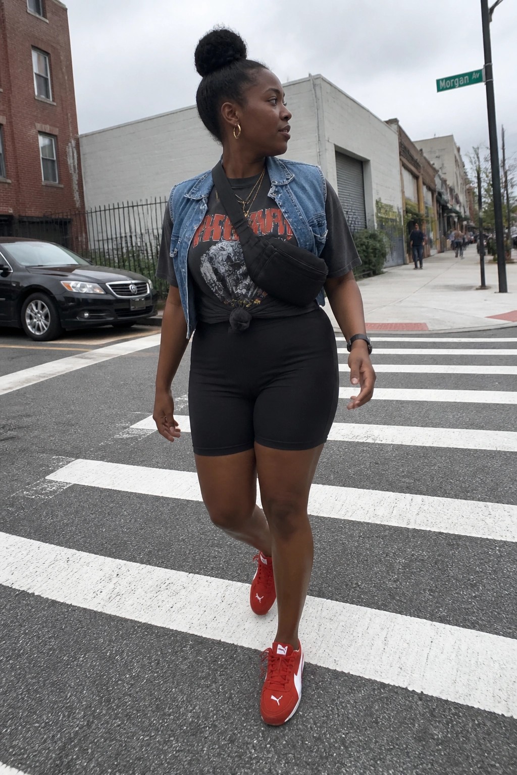Woman in denim vest and red sneakers crossing city crosswalk