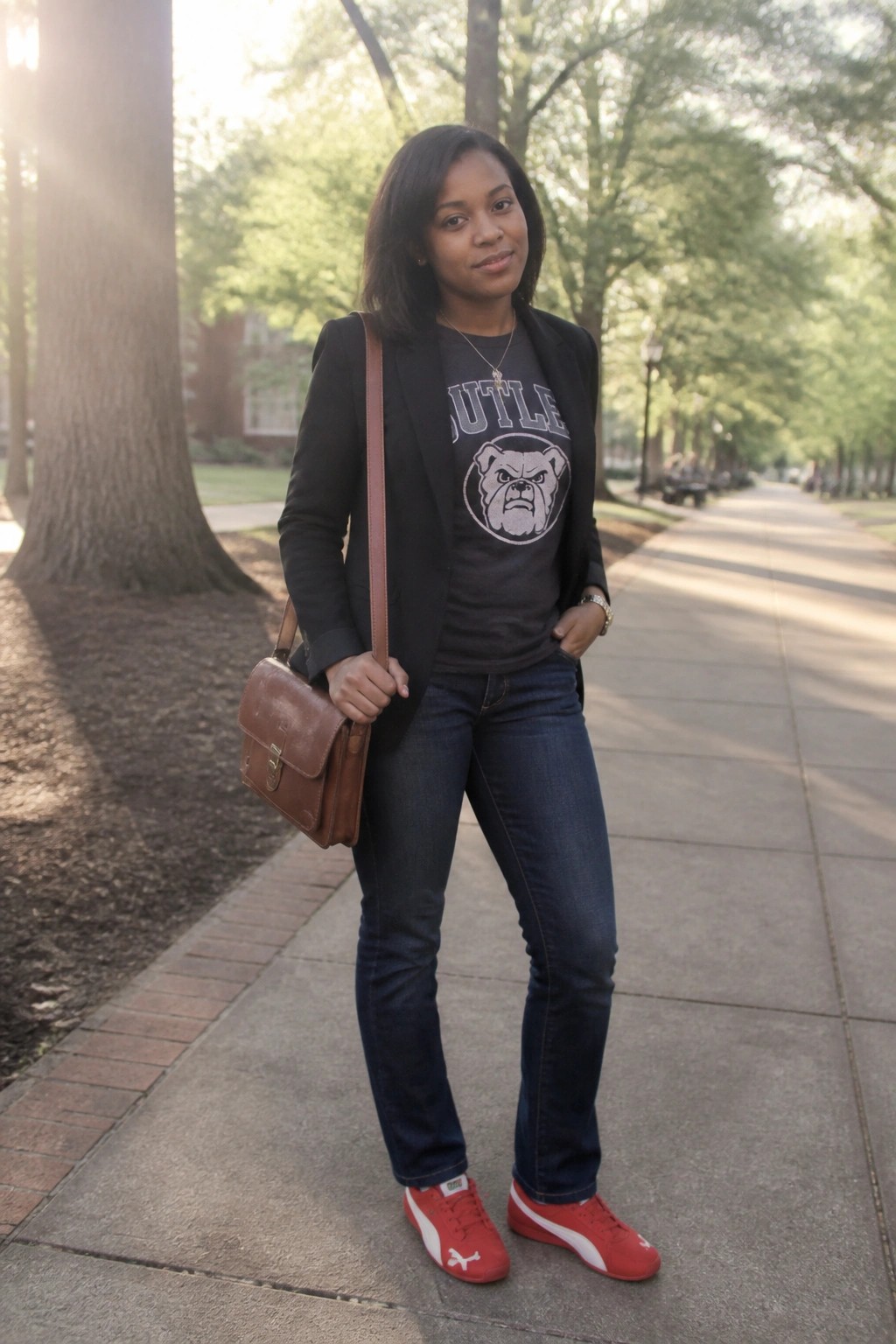 Woman in black blazer over Butler bulldog t-shirt, jeans and red sneakers on path.
