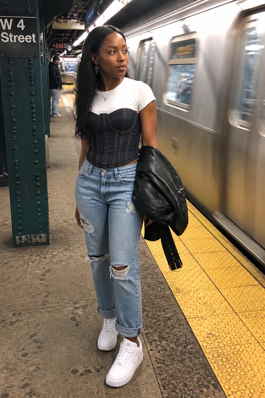 Woman in black denim corset, white tee, and ripped jeans on subway platform