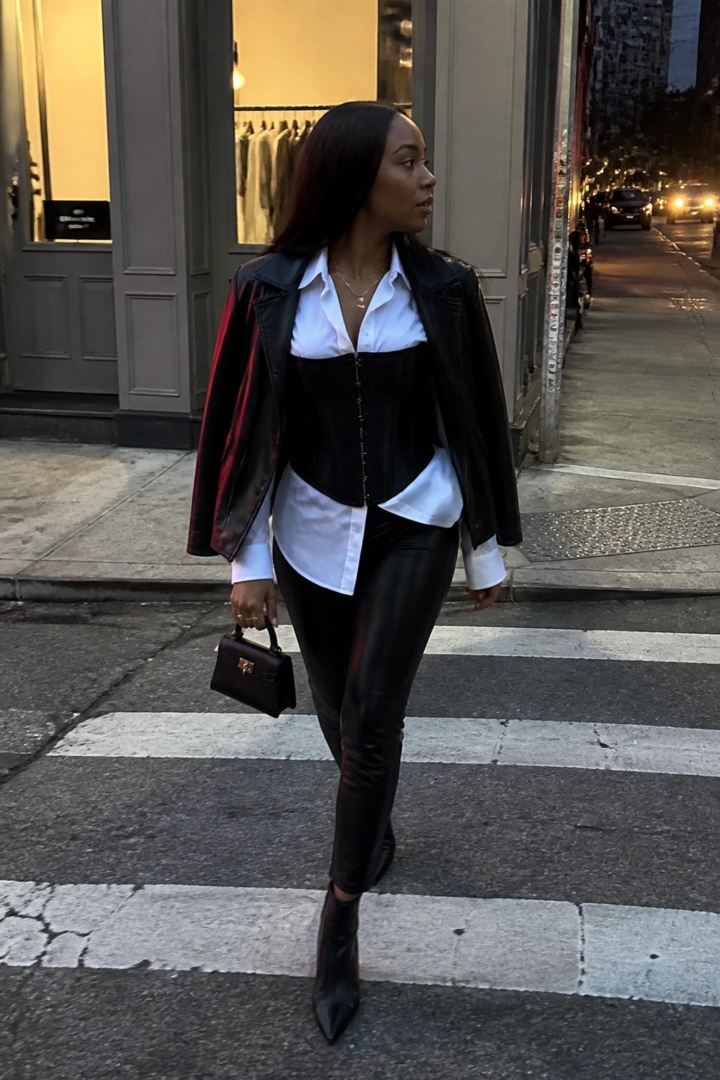 Woman in black leather jacket, corset, white shirt, and pants on city crosswalk