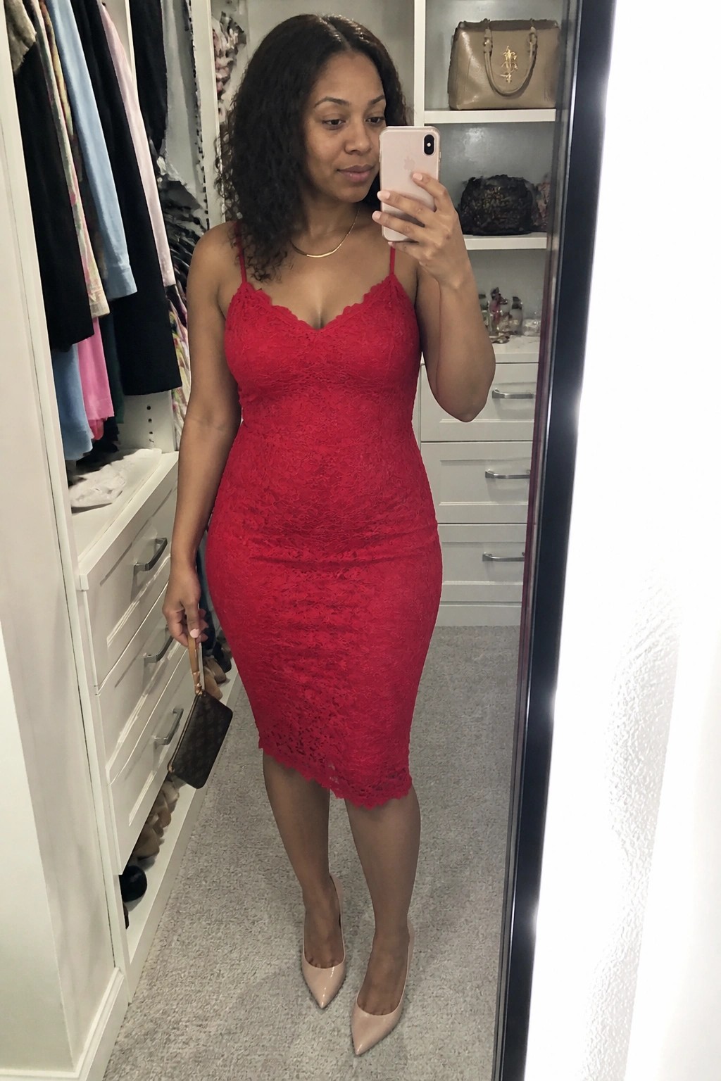 Woman in red lace dress taking mirror selfie in walk-in closet