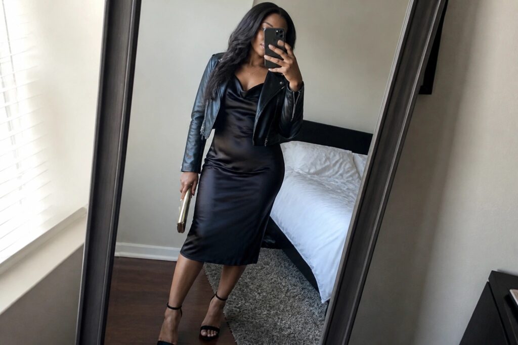20 Chic Fall Club Outfit Ideas for Black Women Woman in black leather jacket and satin dress taking mirror selfie in bedroom