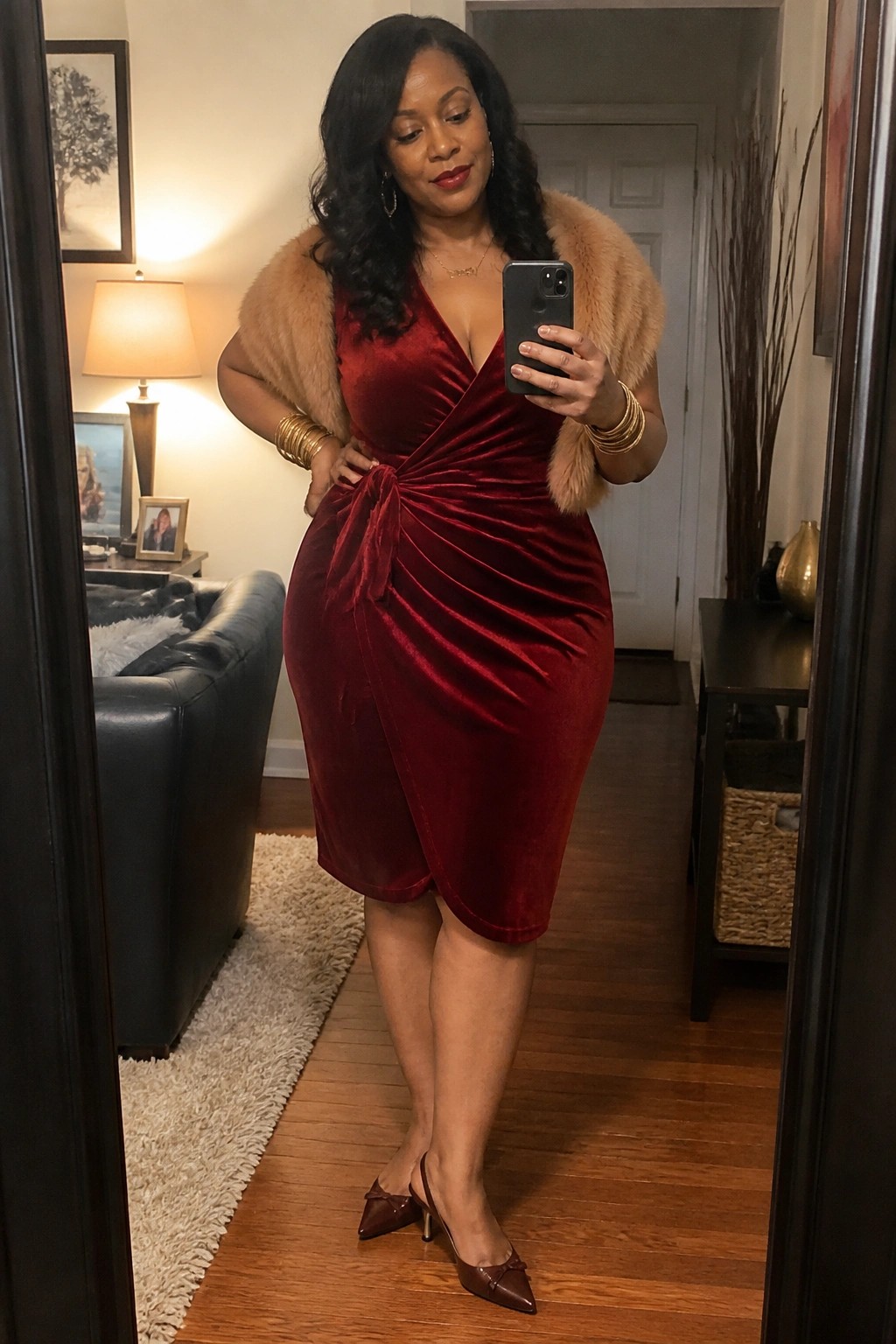 Woman in red velvet wrap dress with fur shawl taking mirror selfie in home