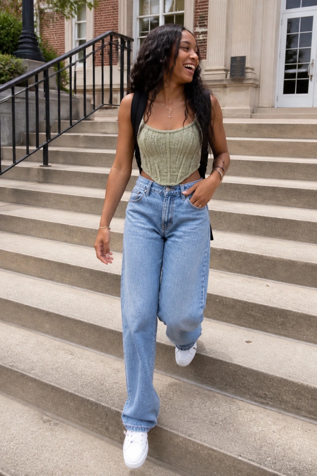 Curly-haired woman in green crop top and blue jeans on stone steps with backpack