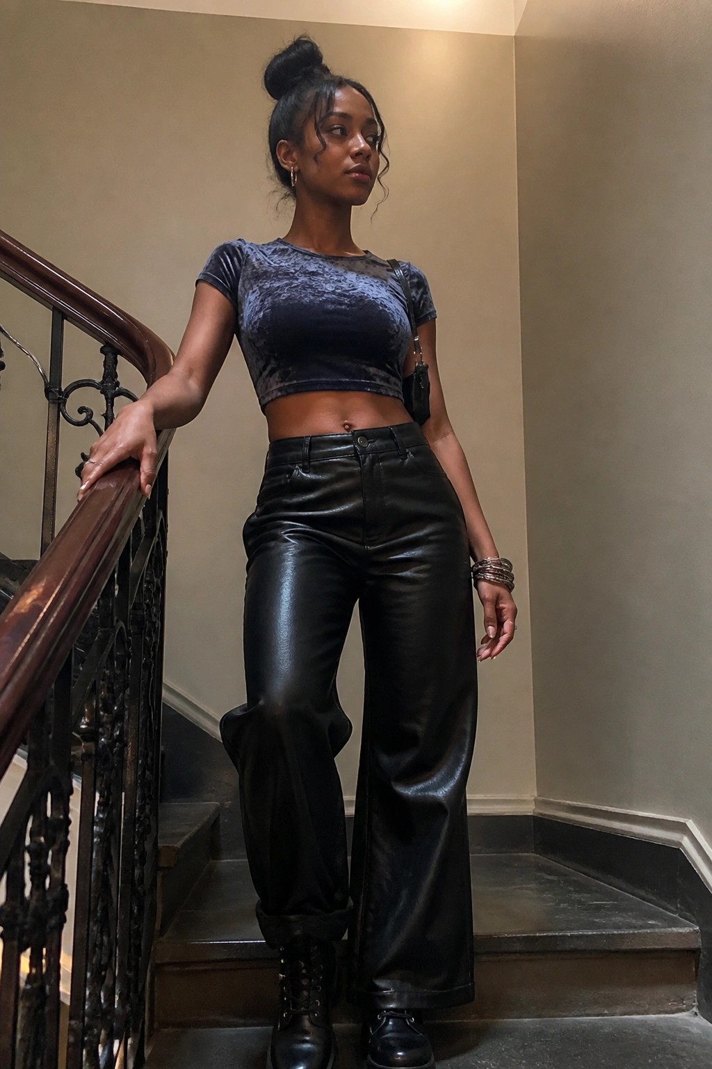 Woman in blue velvet crop top and black leather pants on staircase