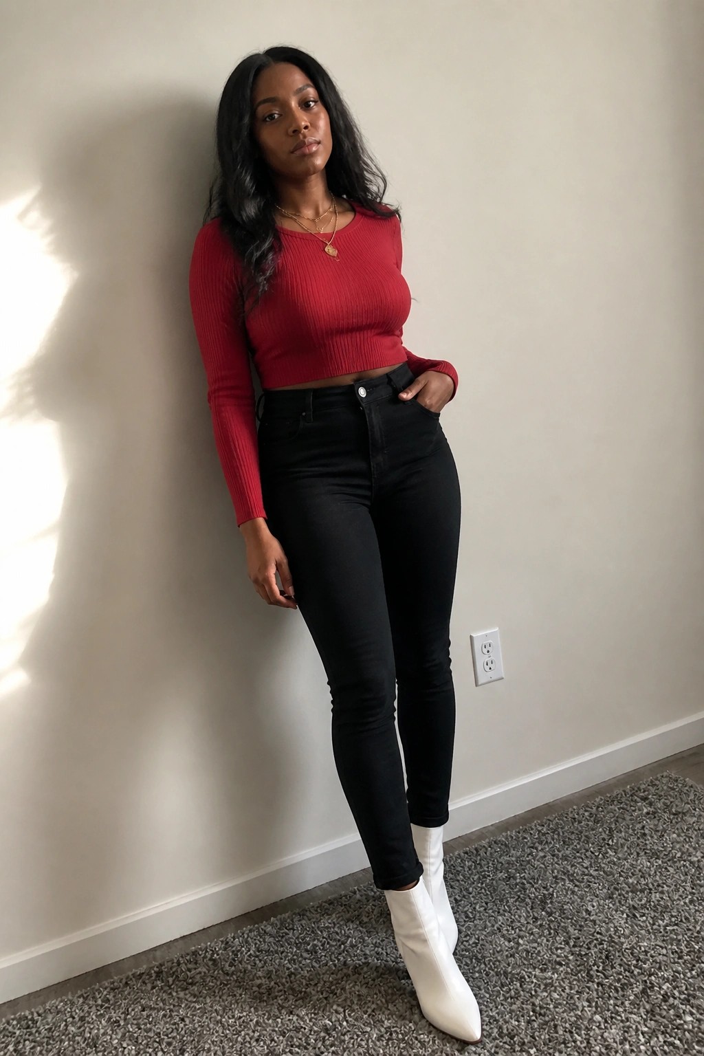 Woman in red crop top and black jeans with white ankle boots by wall