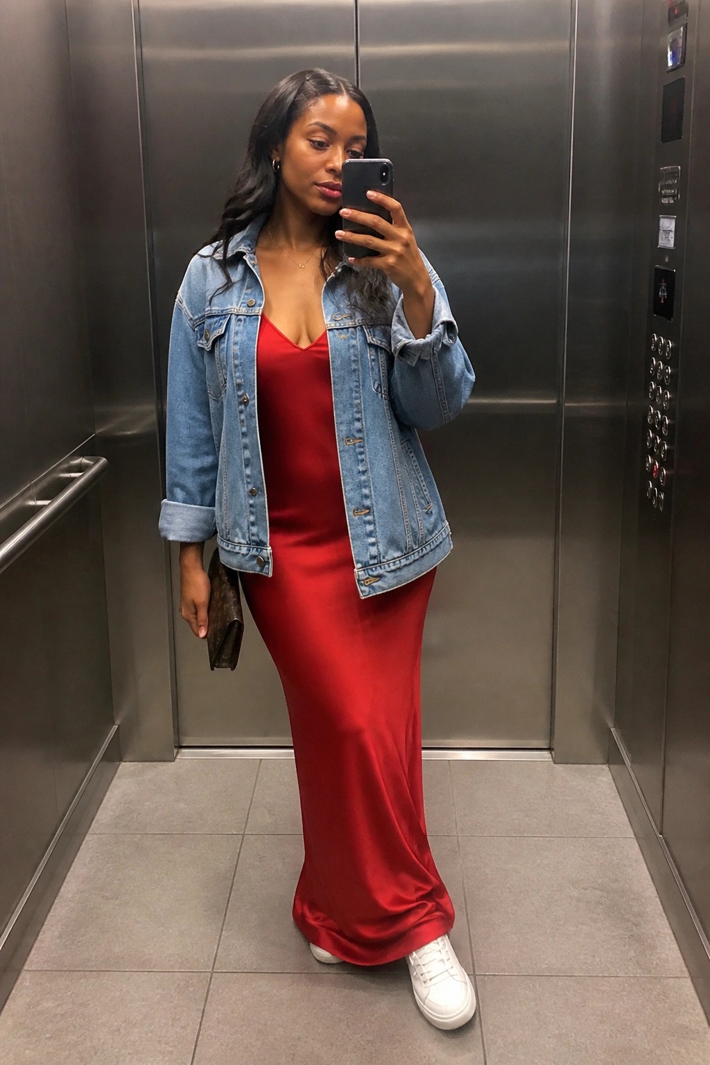 Woman in red dress and denim jacket taking selfie in elevator with white sneakers