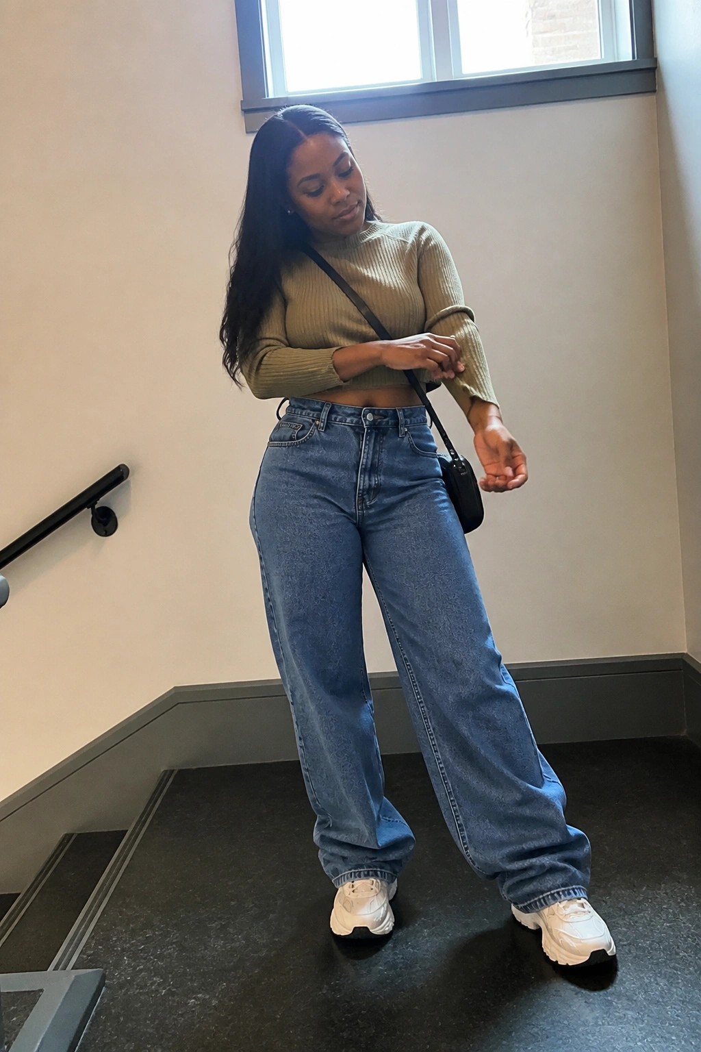 Woman in olive ribbed crop top and wide-leg blue jeans with white sneakers