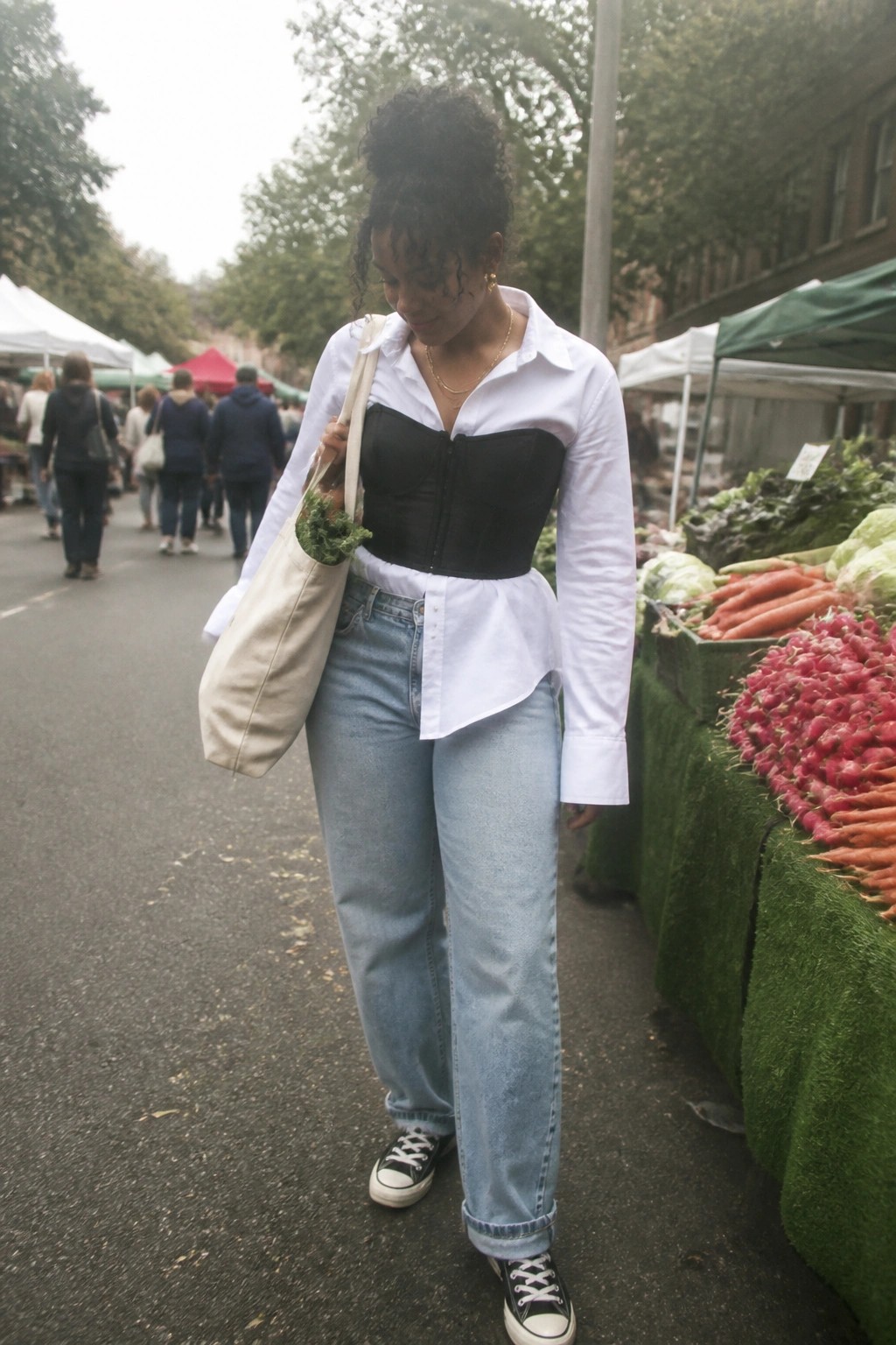 Woman in white shirt over black corset with tote bag at produce market