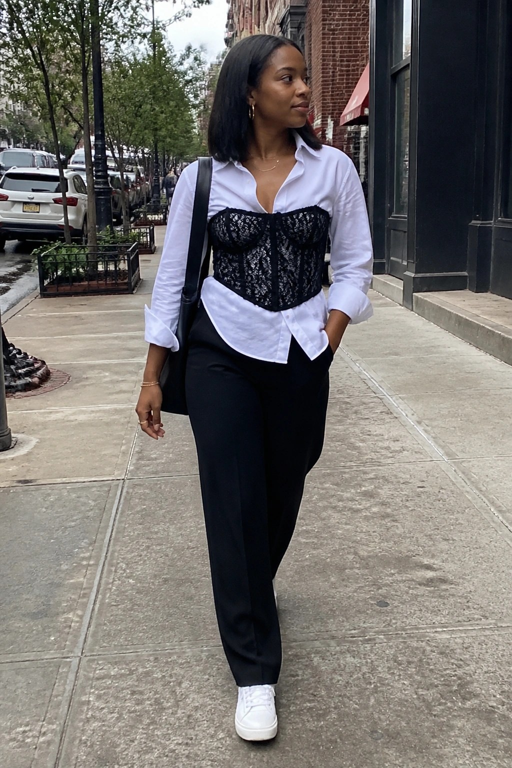 Woman in white shirt and black lace corset walking on city sidewalk