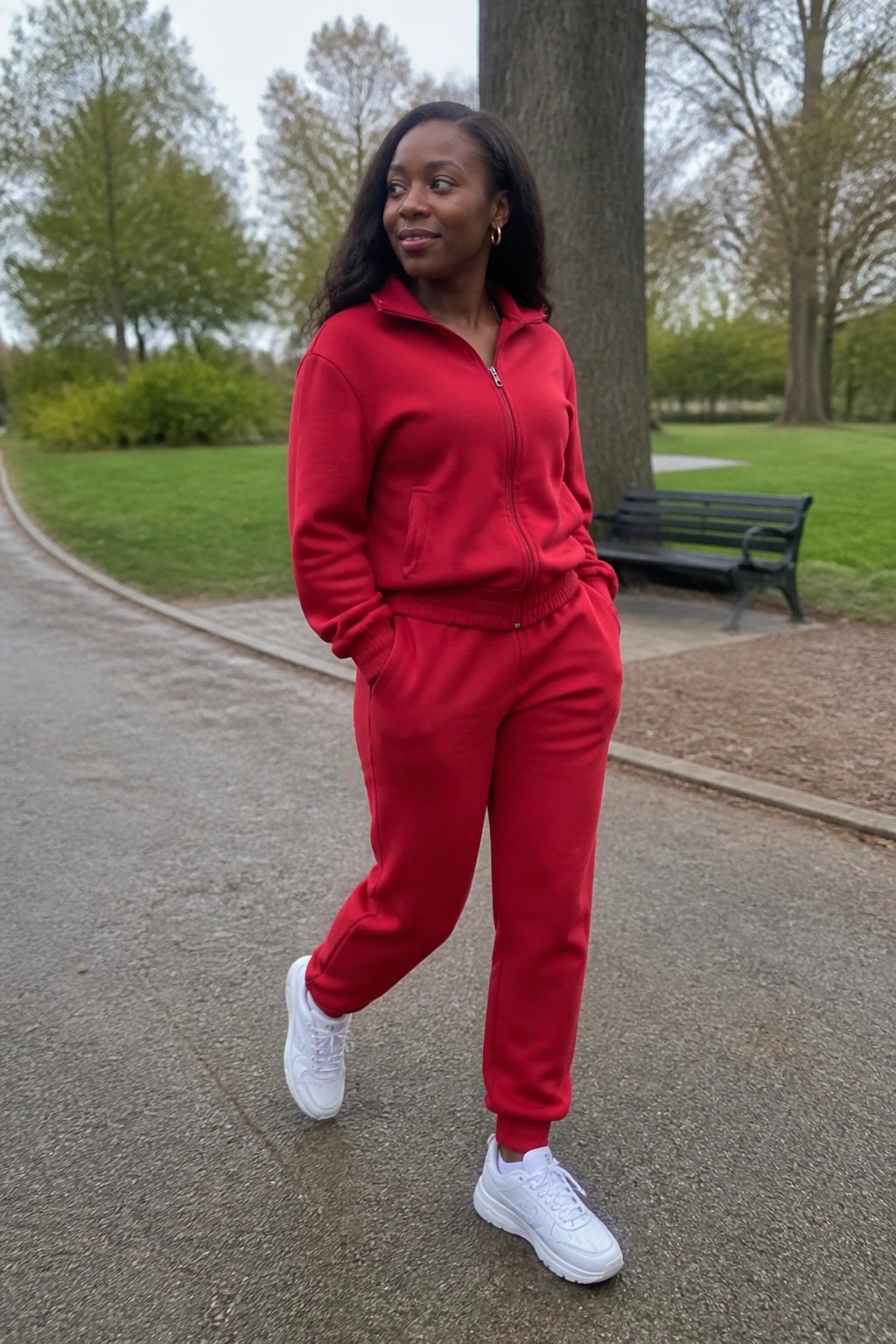 Woman in red tracksuit and white sneakers posing on park path