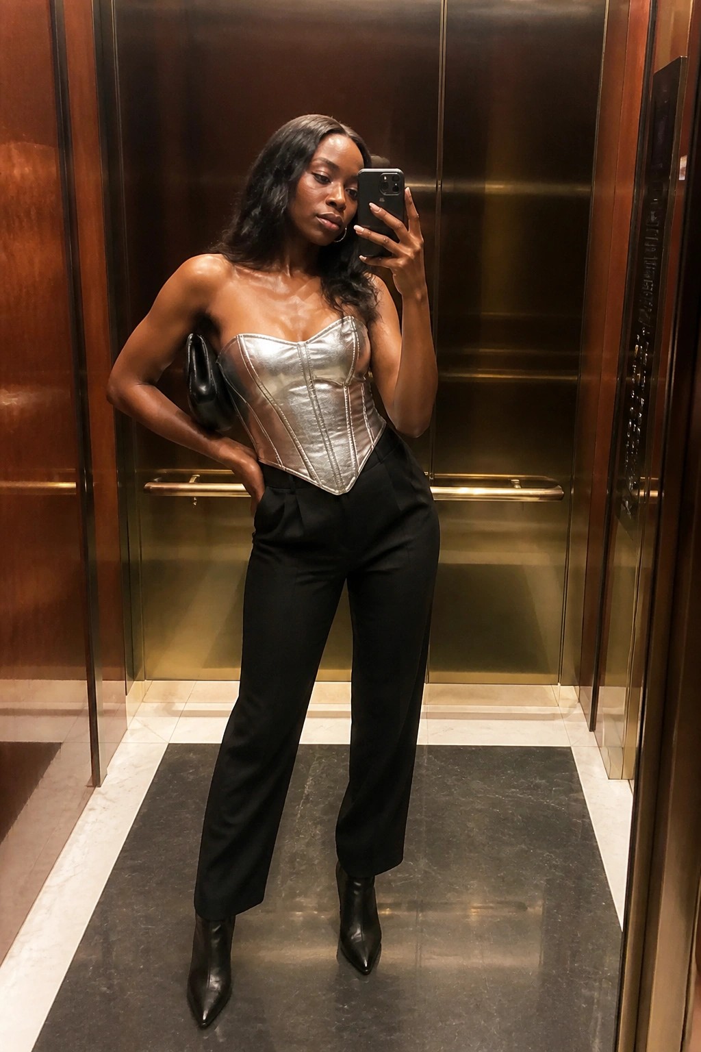 Woman in silver metallic corset and black trousers taking elevator selfie