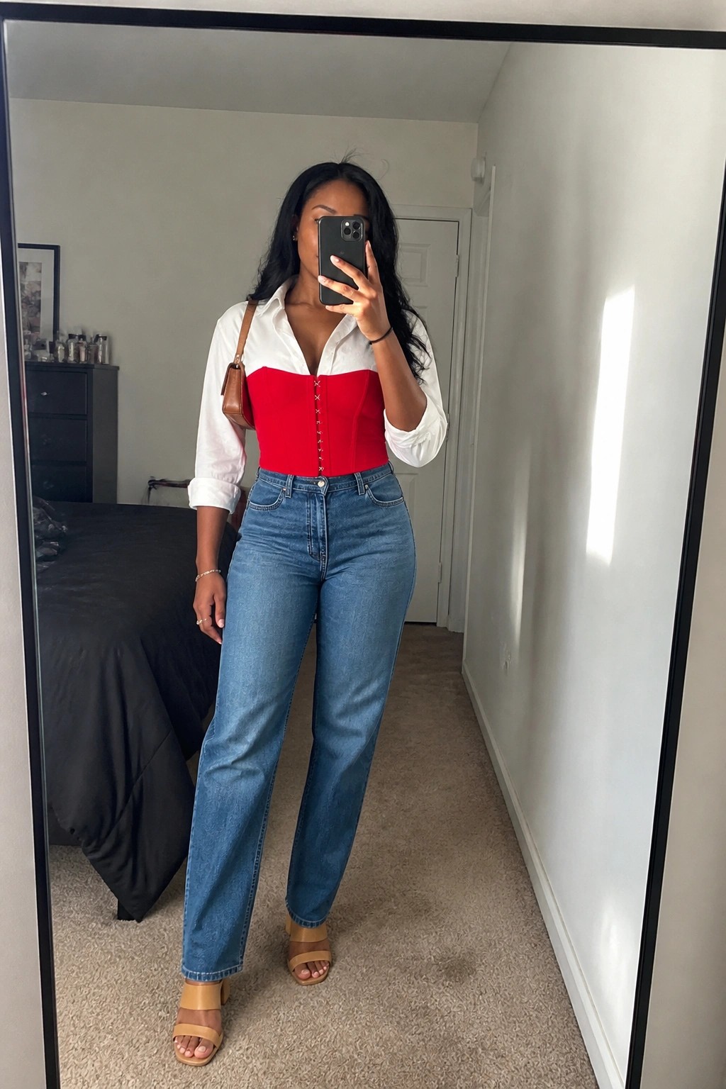 Woman in red corset over white shirt with blue jeans taking mirror selfie