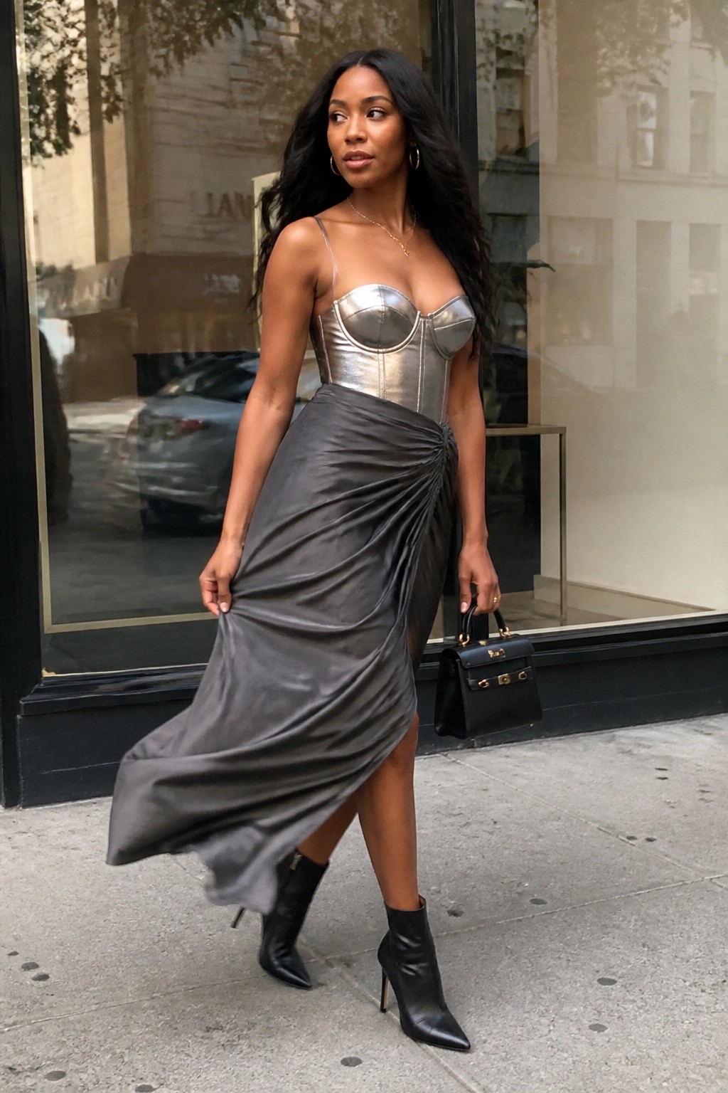 Woman in silver corset and ruched gray skirt with black boots on sidewalk