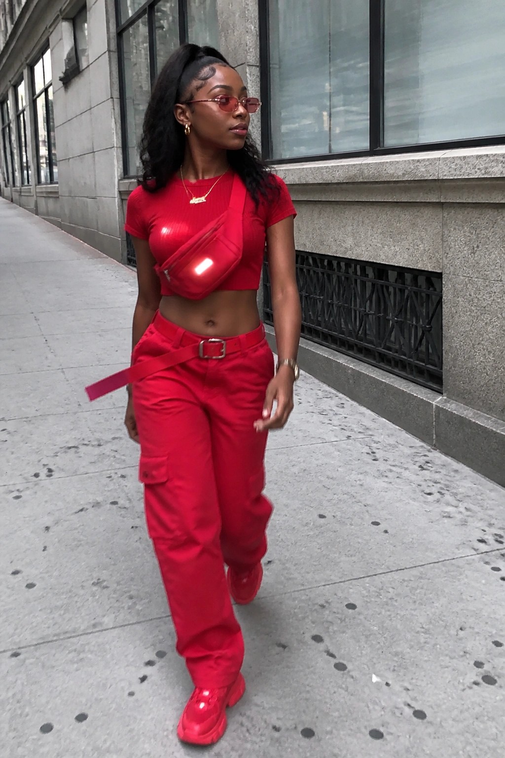 Woman in red crop top and cargo pants walking on city sidewalk