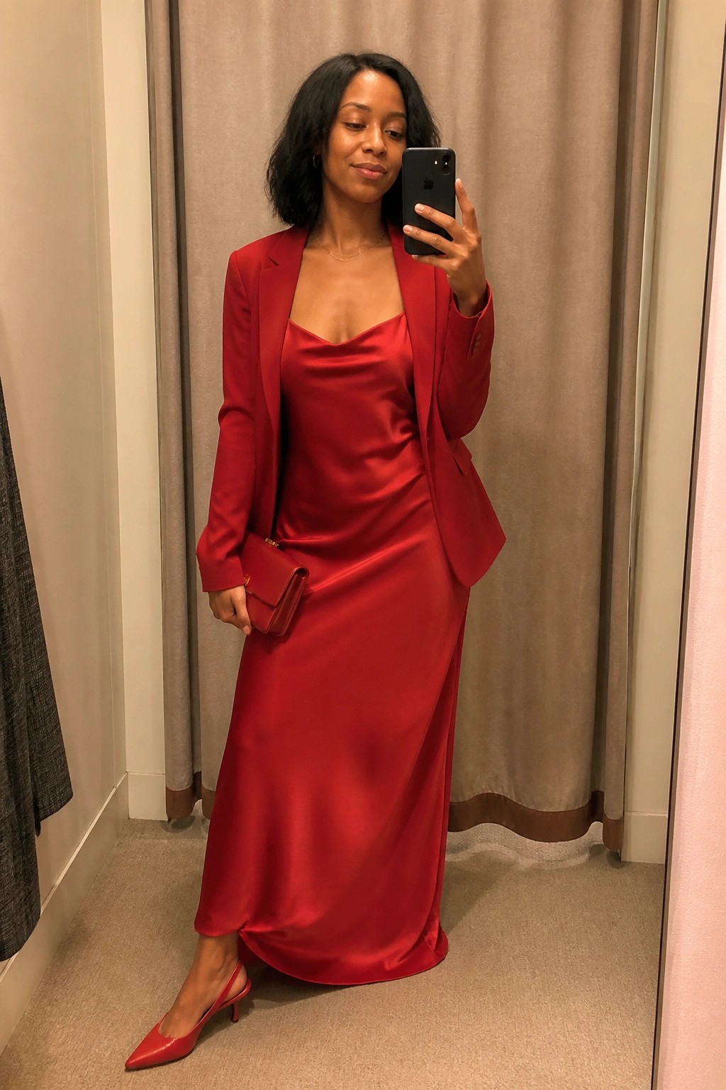 Woman in red satin slip dress and blazer taking mirror selfie with phone