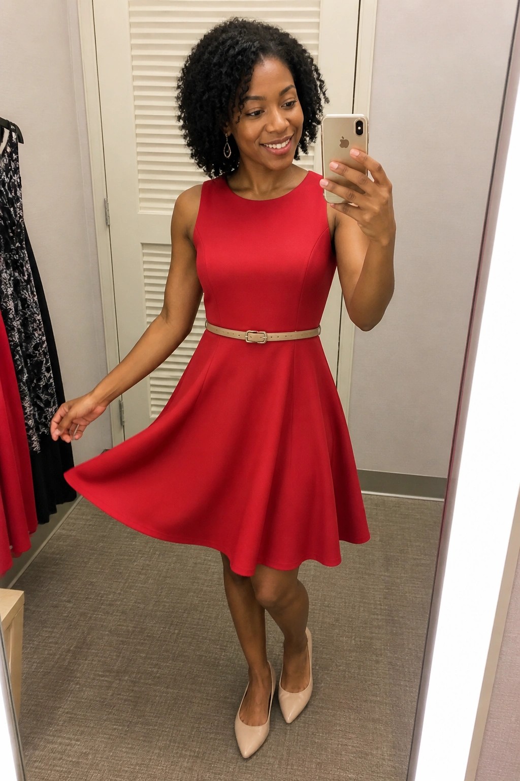 Woman in red dress taking mirror selfie with smartphone in fitting room
