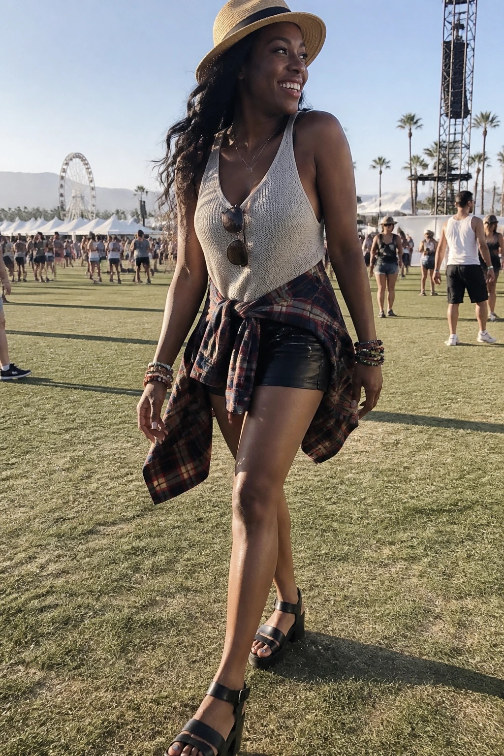 Smiling woman in straw hat, white knit top, plaid shirt at sunny festival