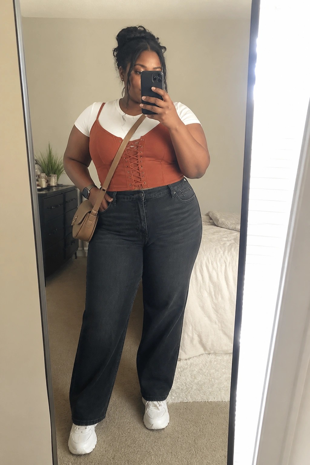 Plus-size woman in orange corset top and wide-leg jeans taking mirror selfie