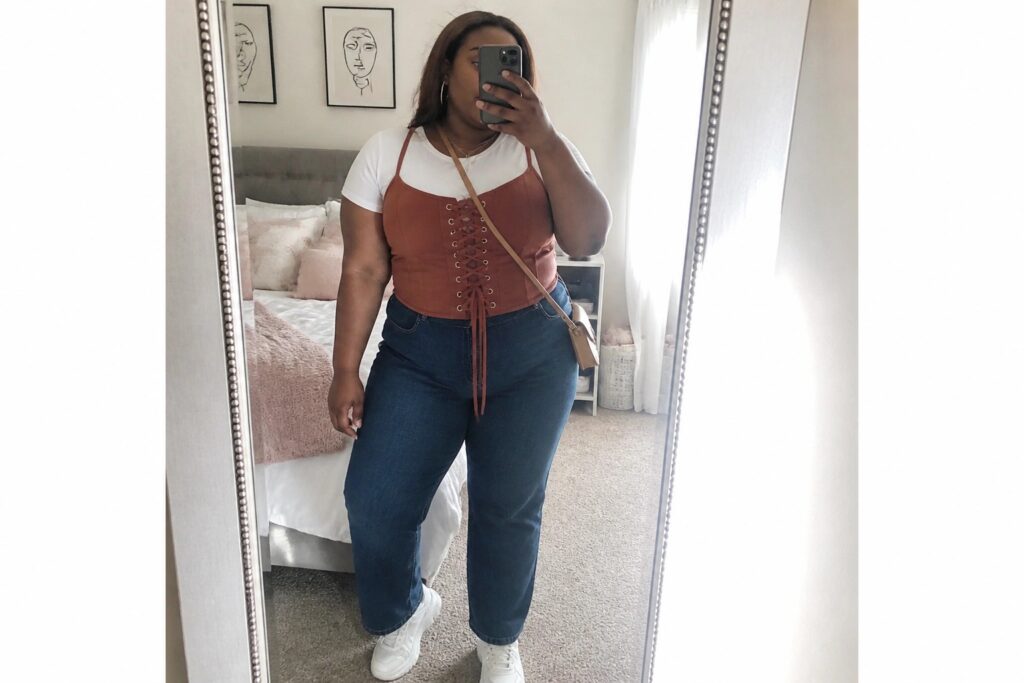 25 Confident Plus Size Corset Outfit Ideas for Black Women Plus-size woman in orange corset top and wide-leg jeans taking mirror selfie