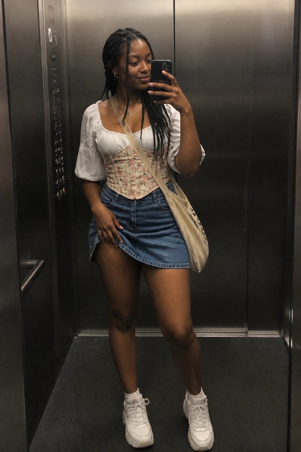 Woman with braids in floral corset and denim skirt taking elevator selfie