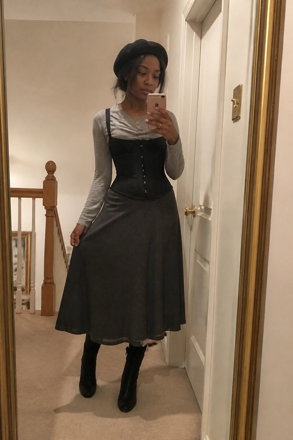 Woman in black beret and corset taking mirror selfie in hallway with phone