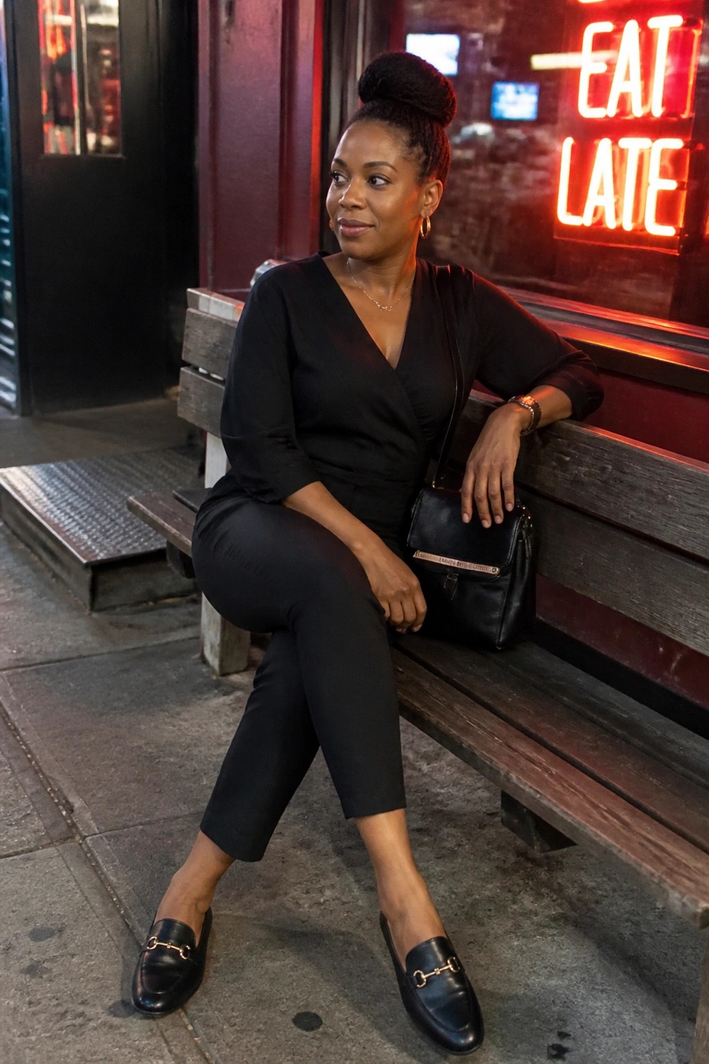 Woman in black outfit seated on bench beside glowing red